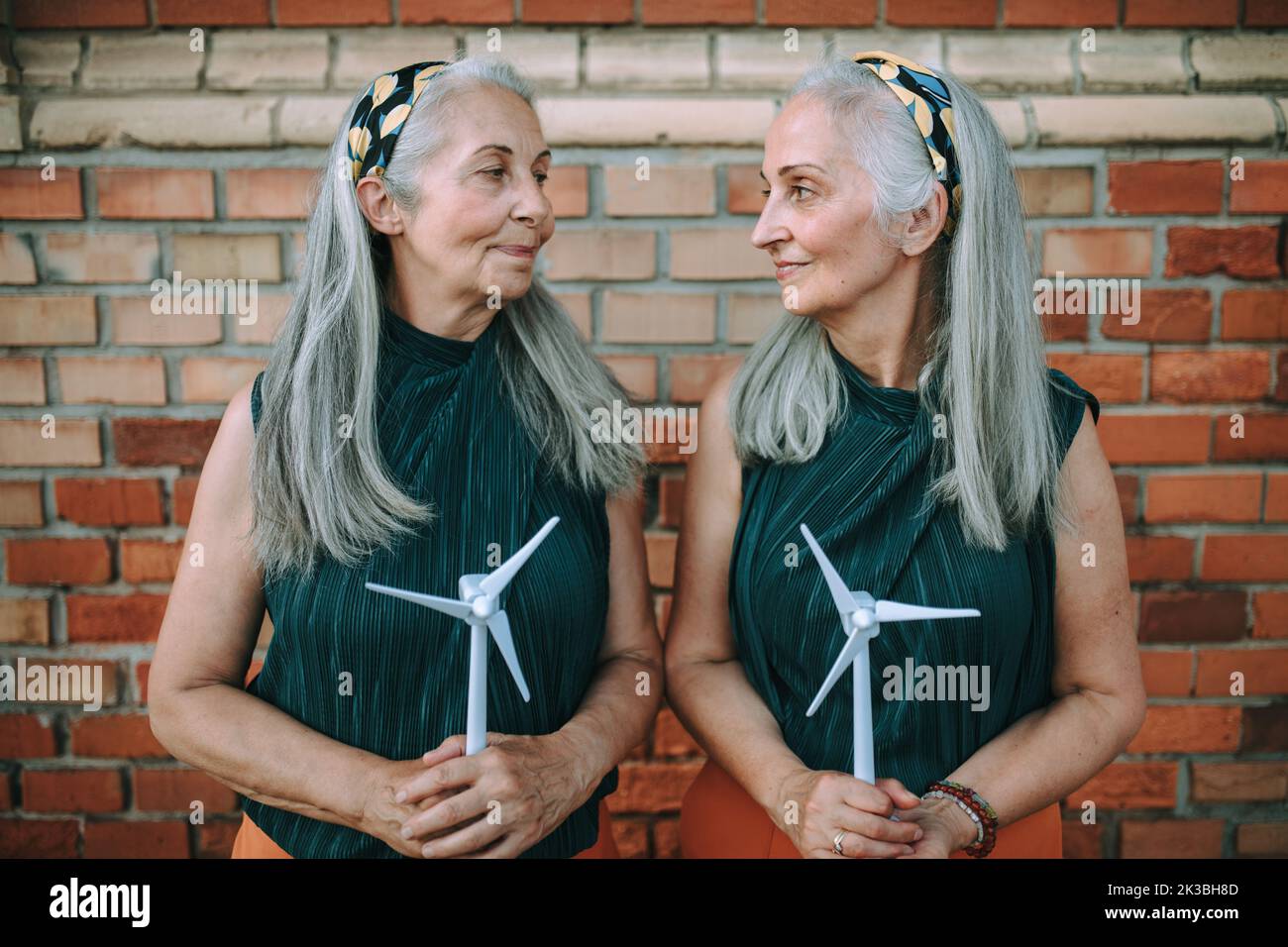 Donne anziane, gemelle con modello plastico di turbina eolica, concetto di futuro, ecologia e risorse rinnovabili, messaggio per la prossima generazione. Foto Stock