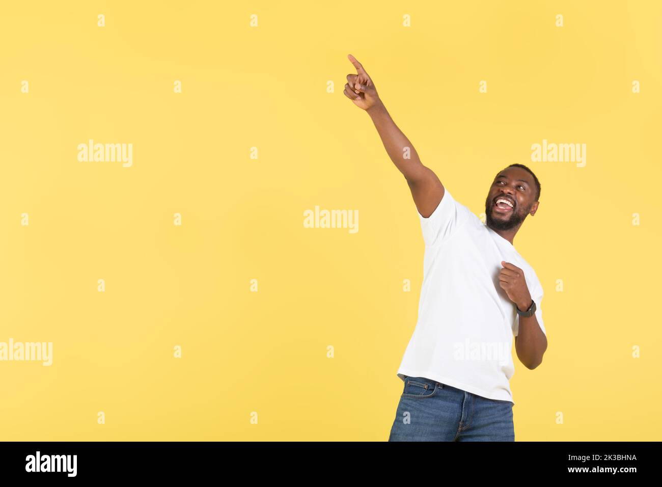African Guy che punta dito in su vicino spazio vuoto, sfondo giallo Foto Stock