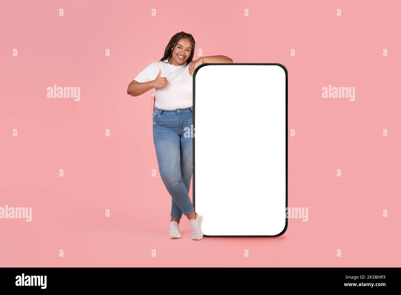 Donna africana che appoggia sullo schermo del cellulare gesturing come, sfondo rosa Foto Stock