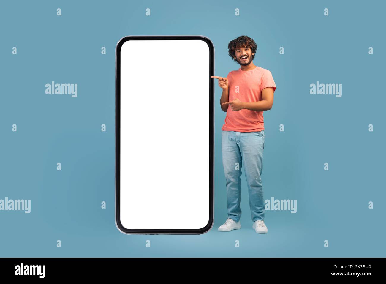 Allegro ragazzo orientale che indica il grande smartphone con schermo vuoto Foto Stock