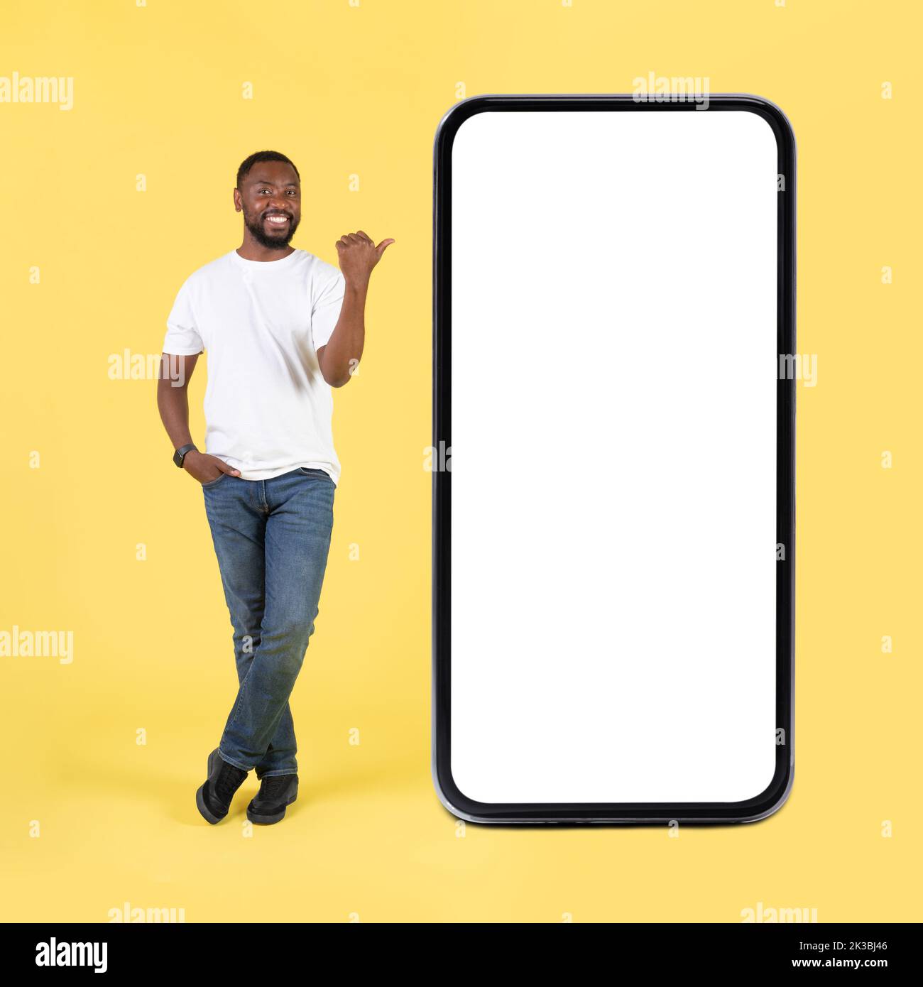 Il ragazzo nero punta il pollice sull'enorme schermo vuoto dello smartphone, Studio Foto Stock