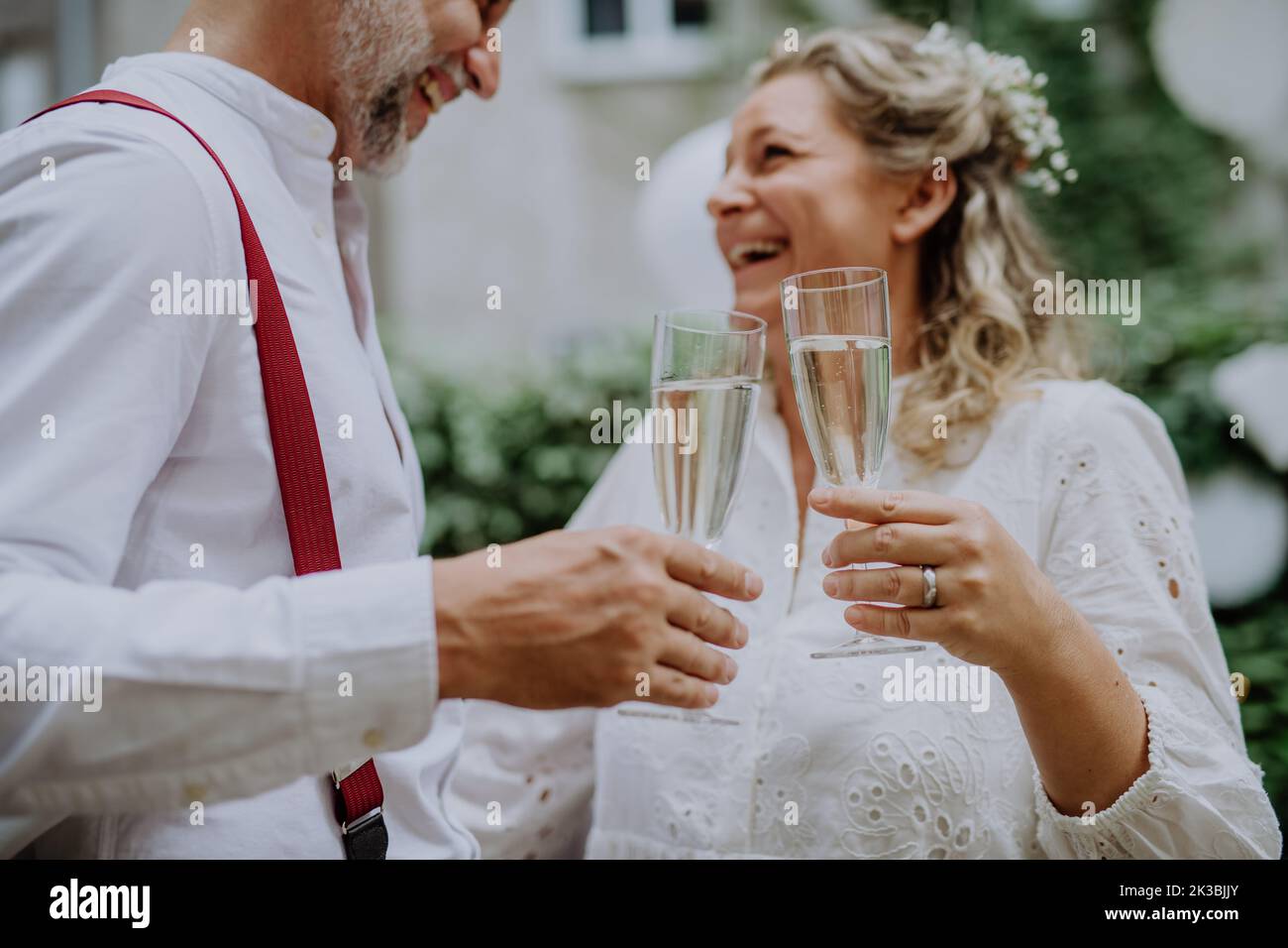 Sposa matura e sposo brinda al ricevimento di nozze all'esterno nel cortile. Foto Stock