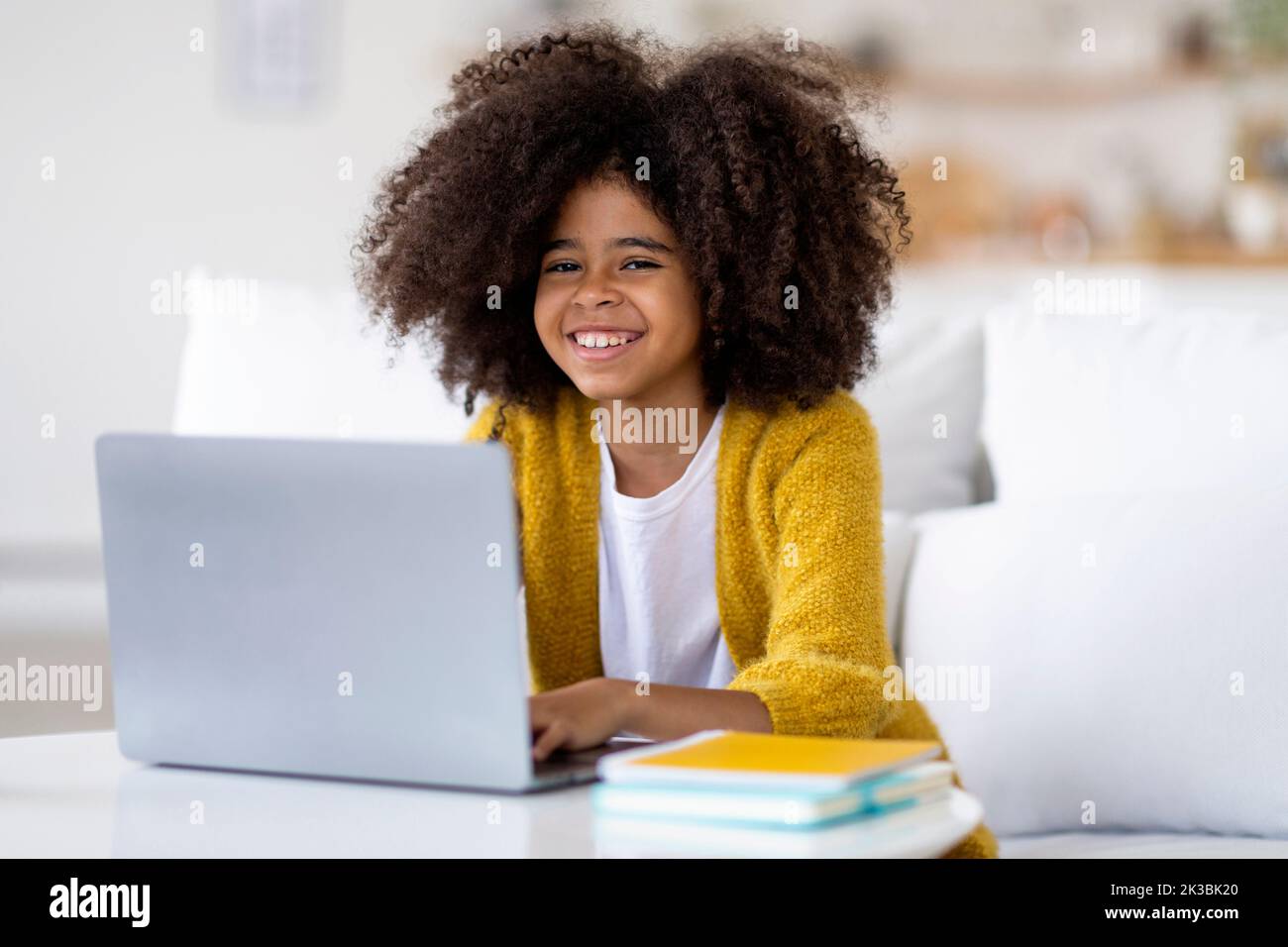 Bambino afroamericano positivo che studia da casa, usando il laptop Foto Stock