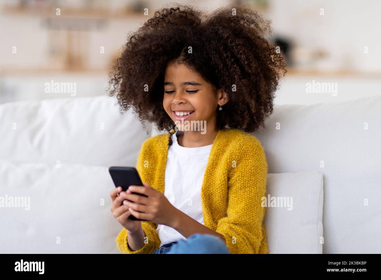 Primo piano di una bambina afroamericana che usa lo smartphone a casa Foto Stock