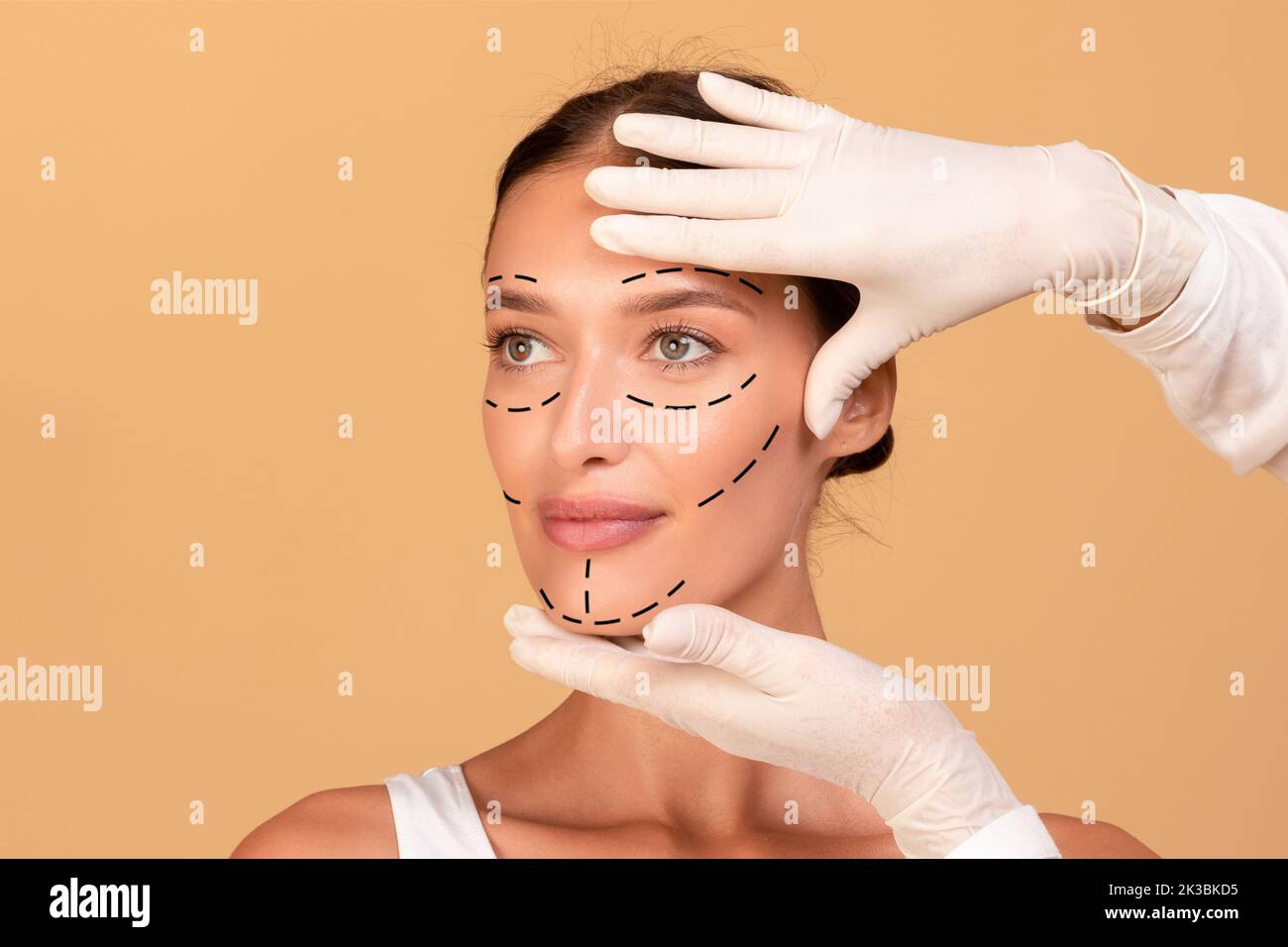 Ritratto frontale della giovane donna che riceve un trattamento termale da estetista, chirurgo plastico facendo segni sul viso femminile Foto Stock