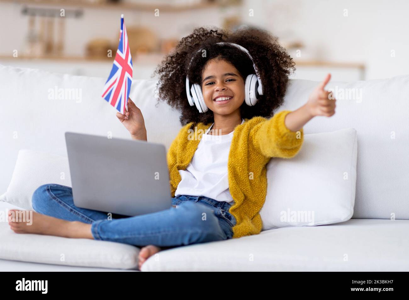 Ragazza nera felice con computer in giro che mostra la bandiera del Regno Unito Foto Stock