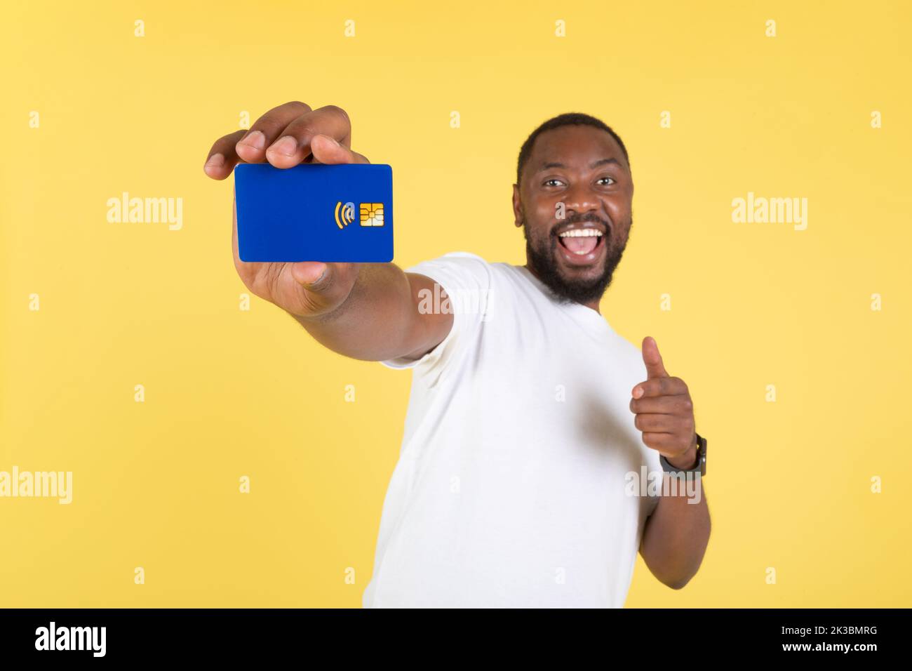 Uomo africano americano felice mostrando carta di credito su sfondo giallo Foto Stock