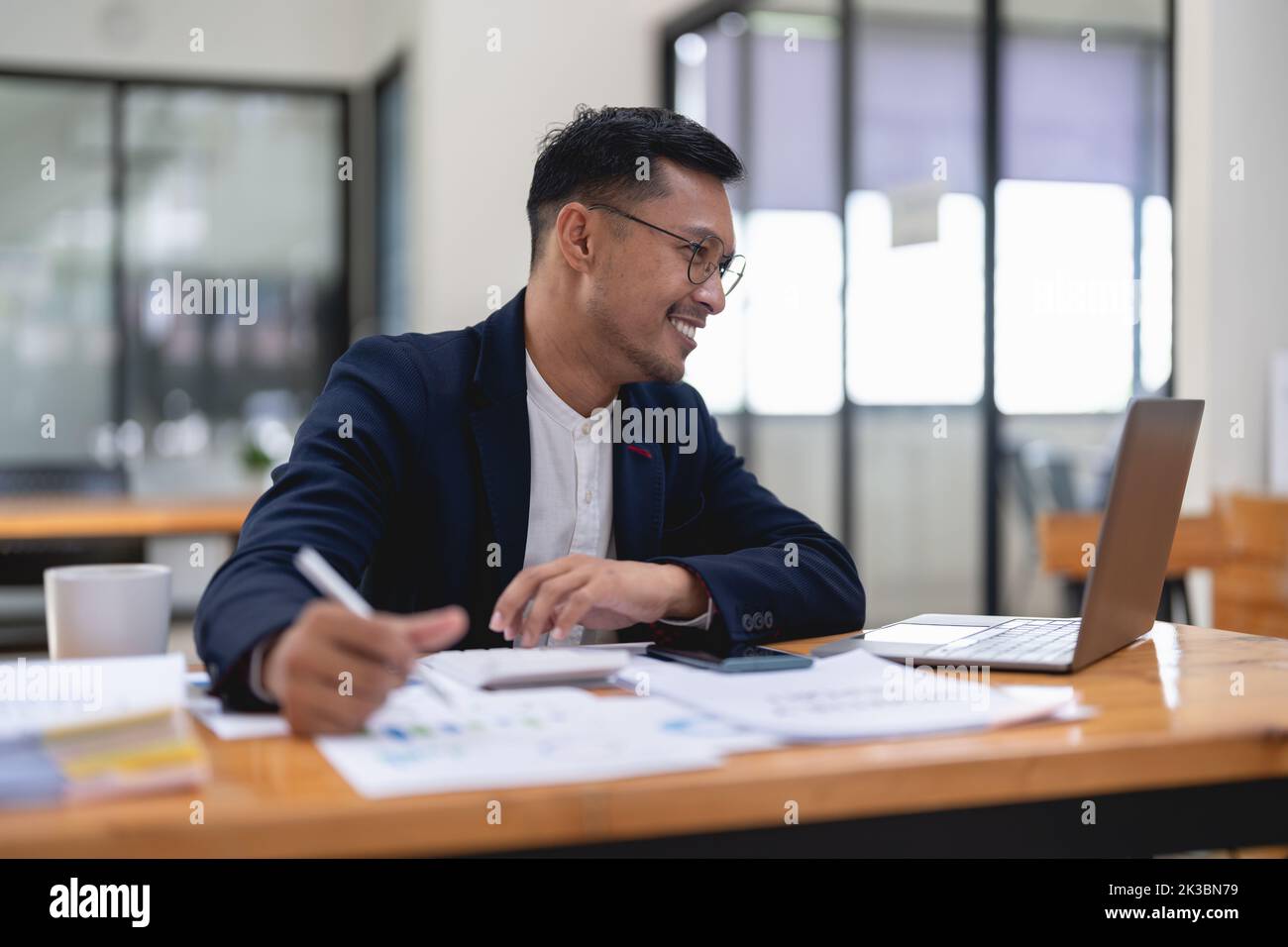 Uomo asiatico che lavora su un computer portatile per l'analisi finanziaria aziendale in ufficio, ritratto. Foto Stock