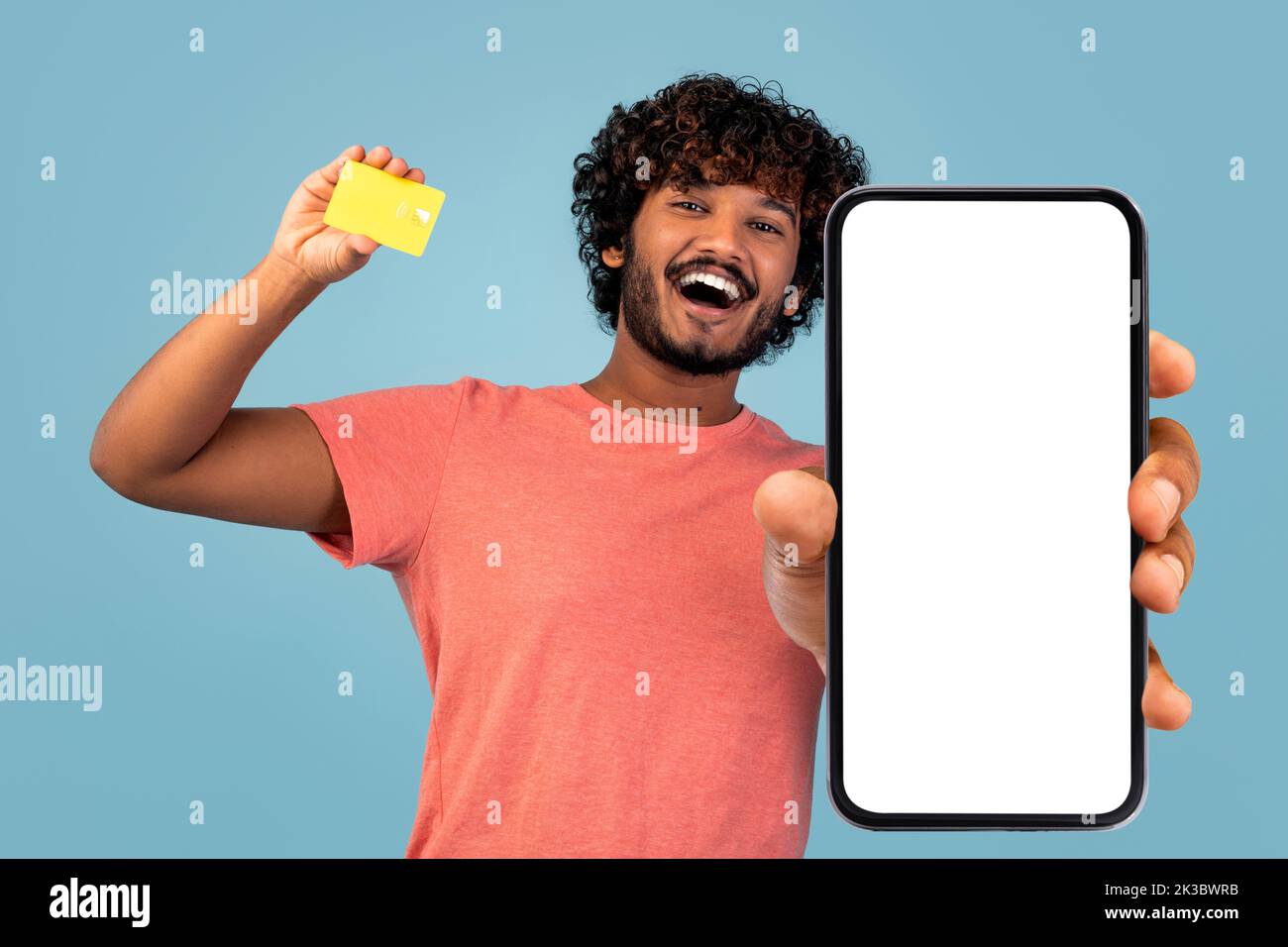 Ragazzo indiano felice che mostra il telefono delle cellule e la carta di credito, mockup Foto Stock