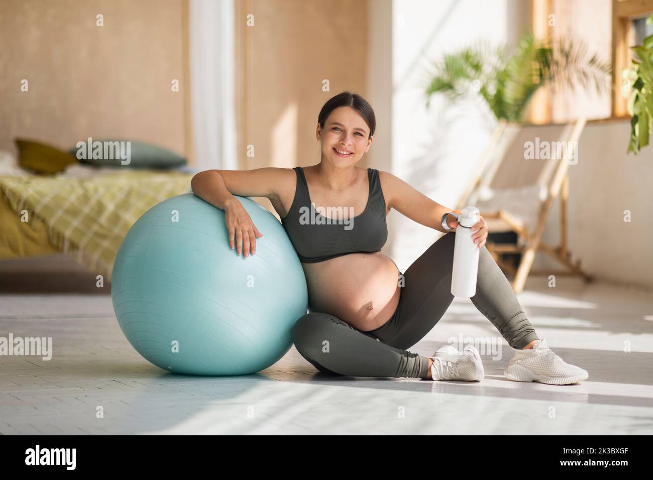 Esercizio fisico e gravidanza. Bella donna incinta in Activewear seduta vicino a Big Fitball Foto Stock