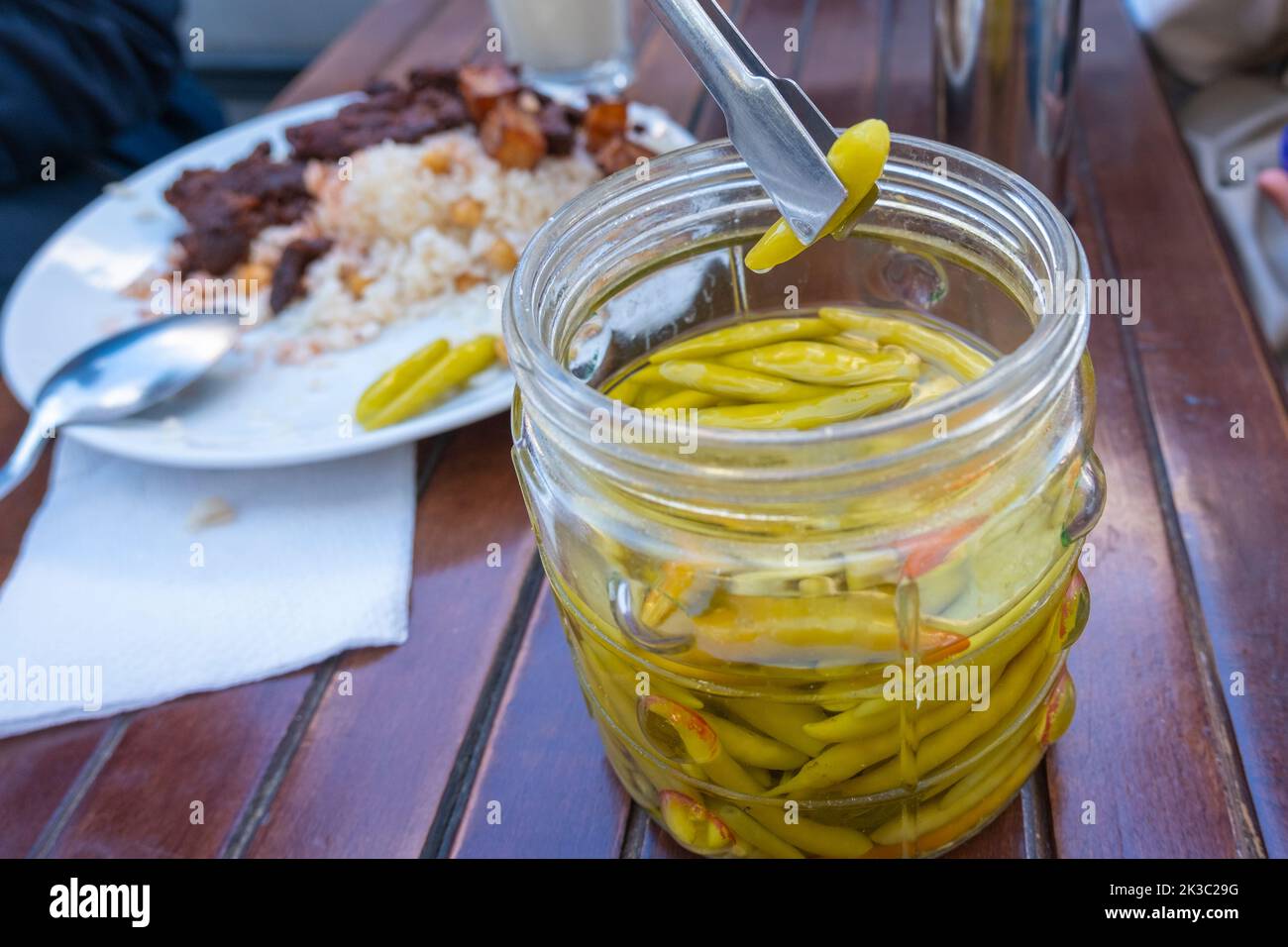 Raccolta di peperoni sott'aceto dal vaso, sottaceti tradizionali turchi, fegato turco e riso sullo sfondo, fuoco selettivo Foto Stock