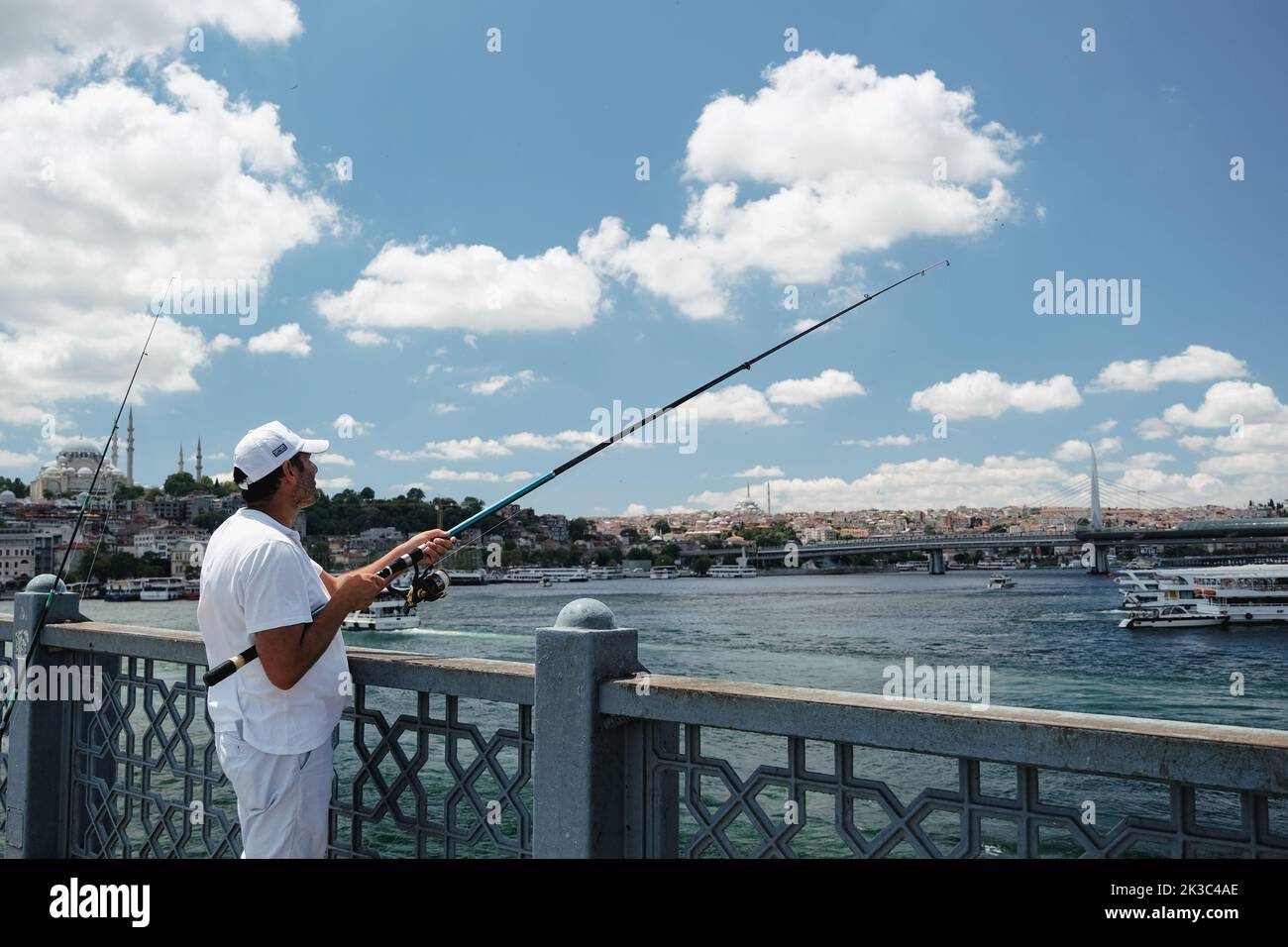 Pescatore grandangolare sul ponte Eminönü Galata, clima nuvoloso, uomo di mezza età in bianco, Turchia Istanbul concetto di turismo, hobby e tempo libero Foto Stock