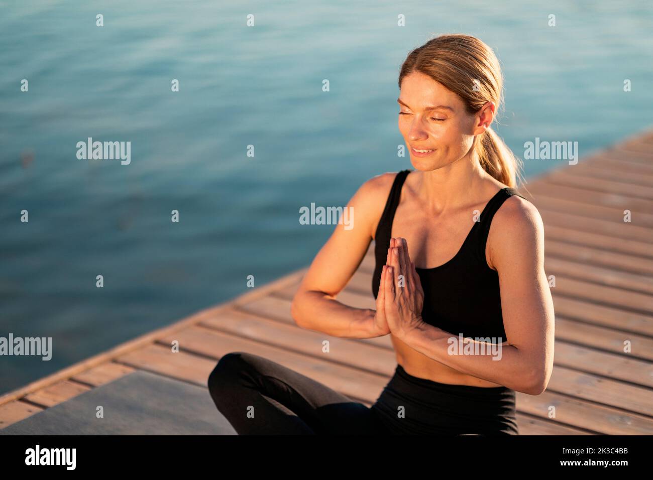 Concetto Namaste. Ritratto di rilassato sportivo di mezza età Femminile meditando all'aperto Foto Stock