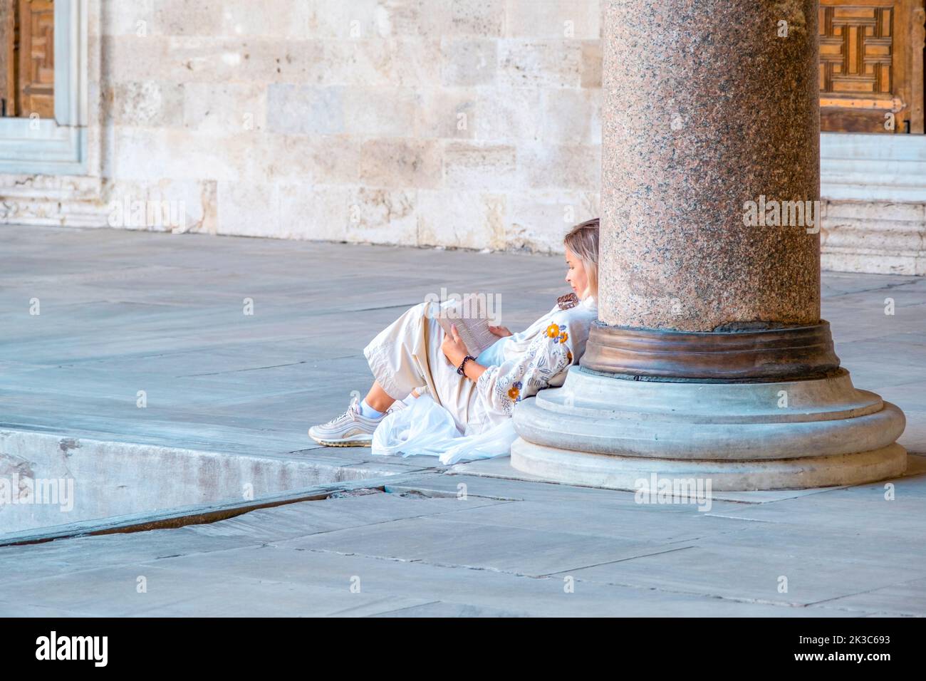 La donna legge un libro nel cortile della Moschea Suleymaniye, leggendo e rilassando l'idea, edificio storico, leggendo il libro e posando il concetto Foto Stock