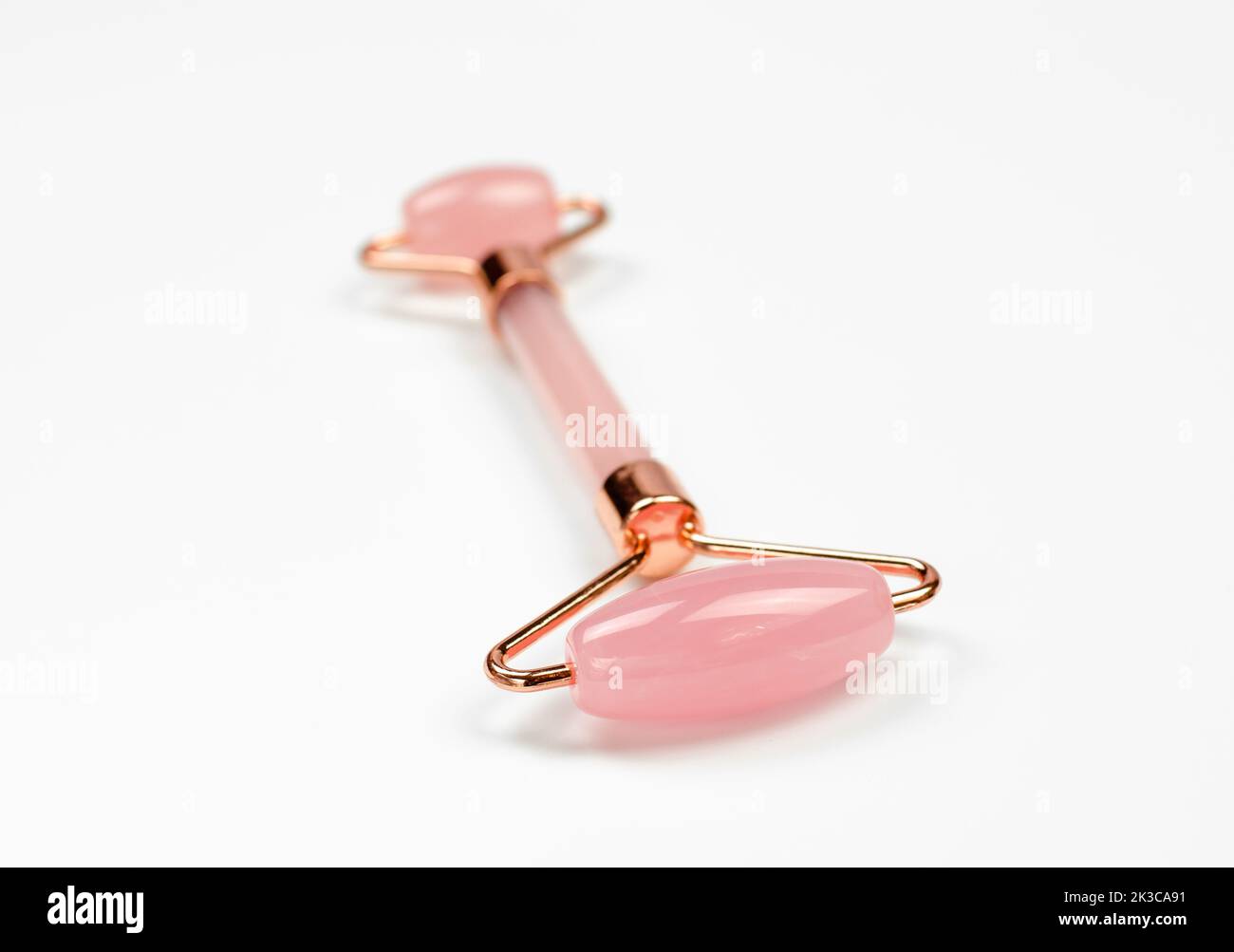 Rullo al quarzo per massaggio gua sha su sfondo bianco, messa a fuoco selettiva Foto Stock