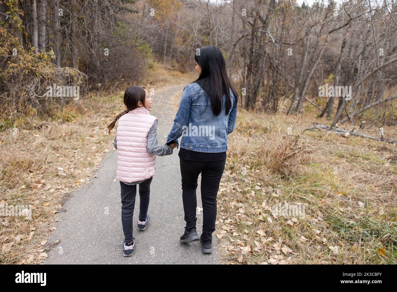 Madre e figlia che tengono le mani sul sentiero del parco autunnale Foto Stock