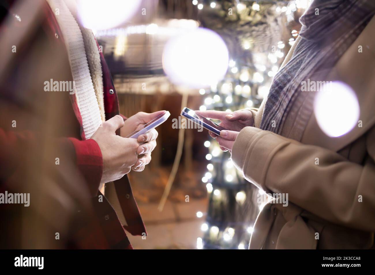 Due persone che utilizzano lo smartphone in una splendida notte d'inverno Foto Stock