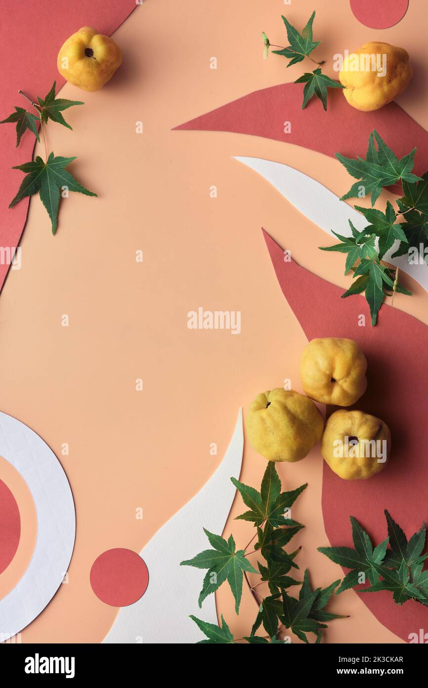 Sfondo autunntime con forme di carta organica, mela cotogna gialla e foglie di acero verde. Sfondo di carta arancione. Arredamento Autumntime naturale Foto Stock