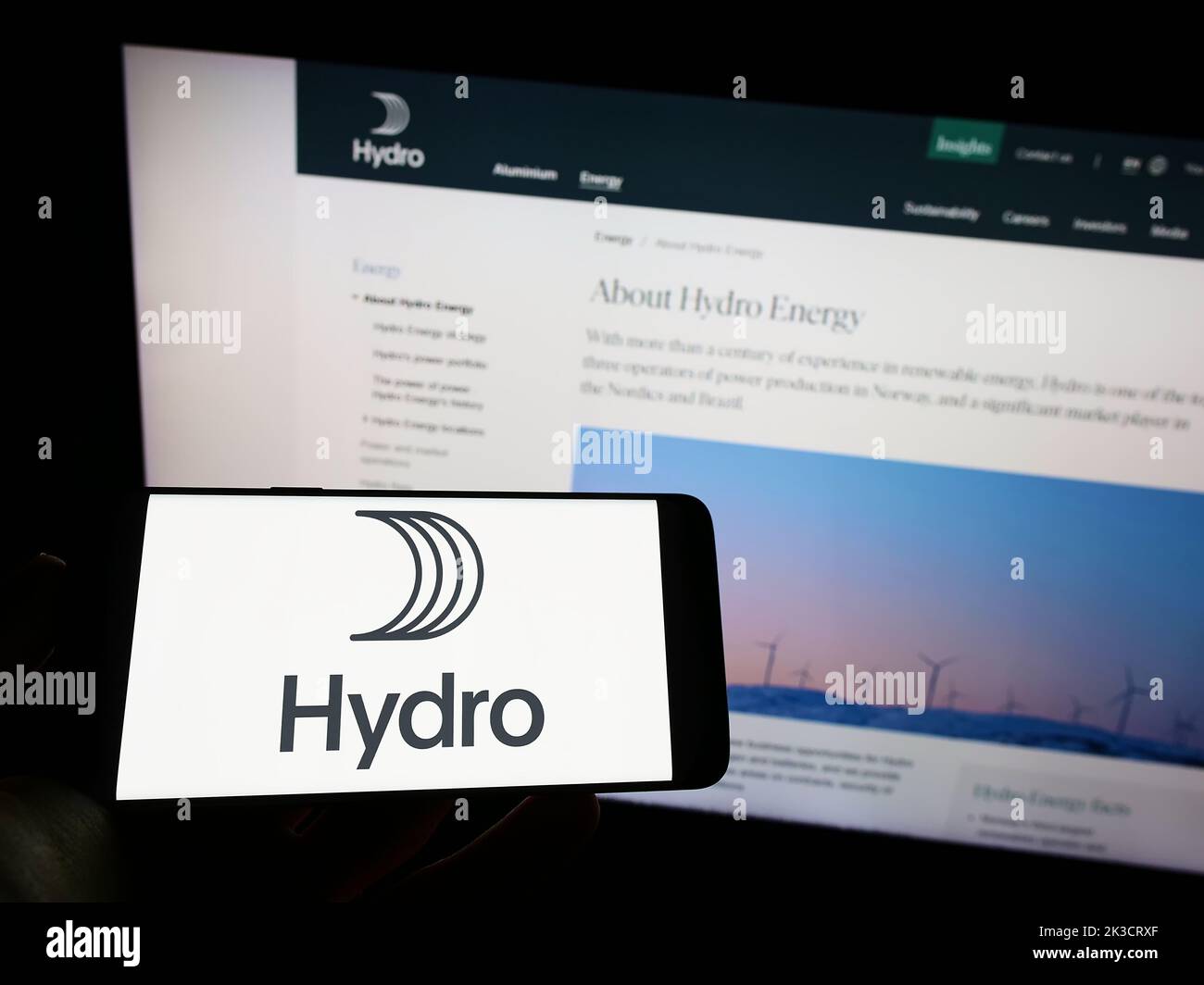 Persona che detiene il telefono cellulare con il logo della società norvegese di alluminio Norsk Hydro ASA sullo schermo di fronte alla pagina web. Messa a fuoco sul display del telefono. Foto Stock