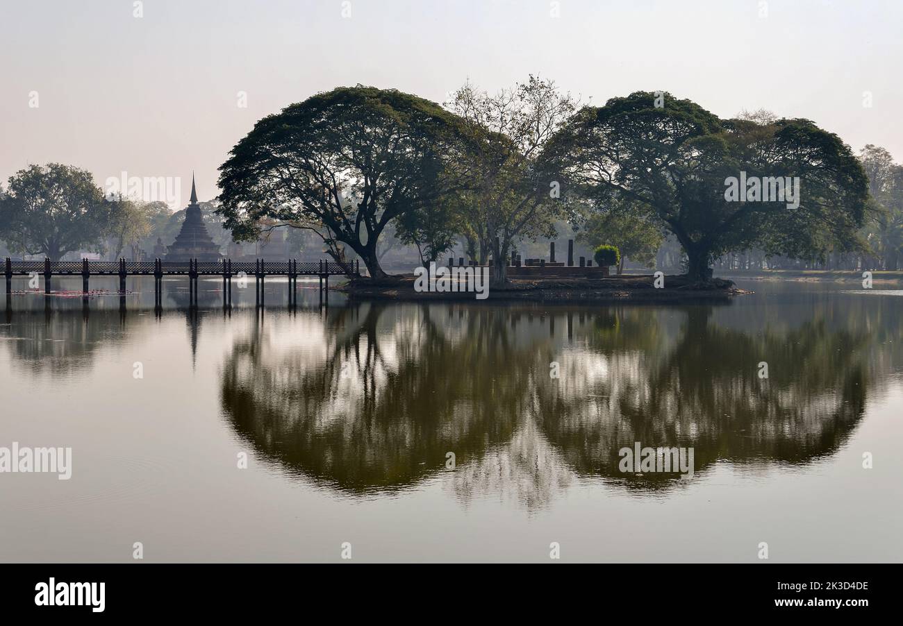 Bella vista mattutina del tempio Wat Trapphang Ngoen all'alba nel Parco storico di Sukhothai, Thailandia. Vecchi alberi che si riflettono sull'acqua come uno specchio. Foto Stock