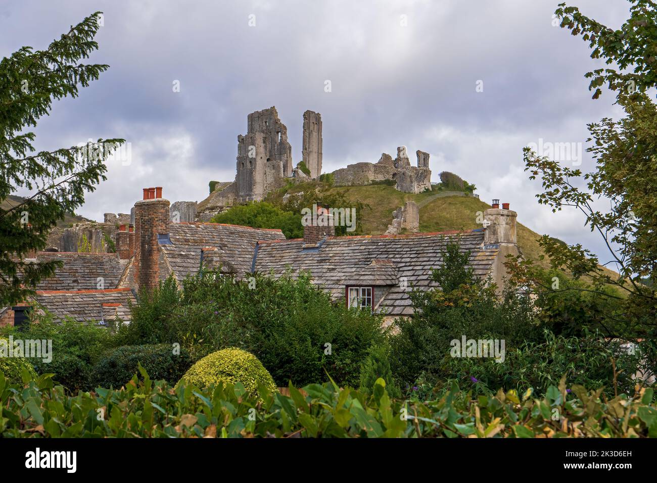 Una vista del castello di Corfe attraverso le vecchie cime di pietra nel villaggio di Corfe, Dorset, Inghilterra, Regno Unito Foto Stock
