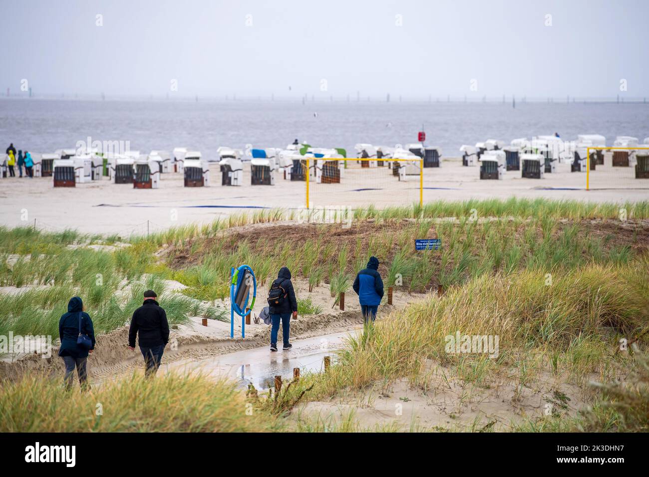 26 settembre 2022, bassa Sassonia, Norden: Camminatori camminano sulla spiaggia di Norddeich sotto la pioggia. Foto: Sina Schuldt/dpa Foto Stock