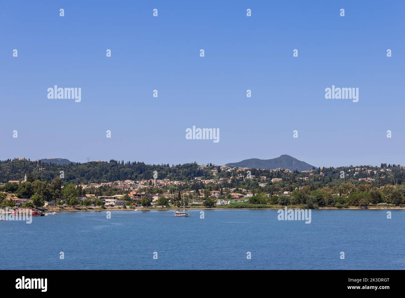 La costa dell'isola di Corfù con aree urbane immerse nel verde tutto l'anno, sotto il cielo blu chiaro del mattino, isole ioniche, Grecia Foto Stock