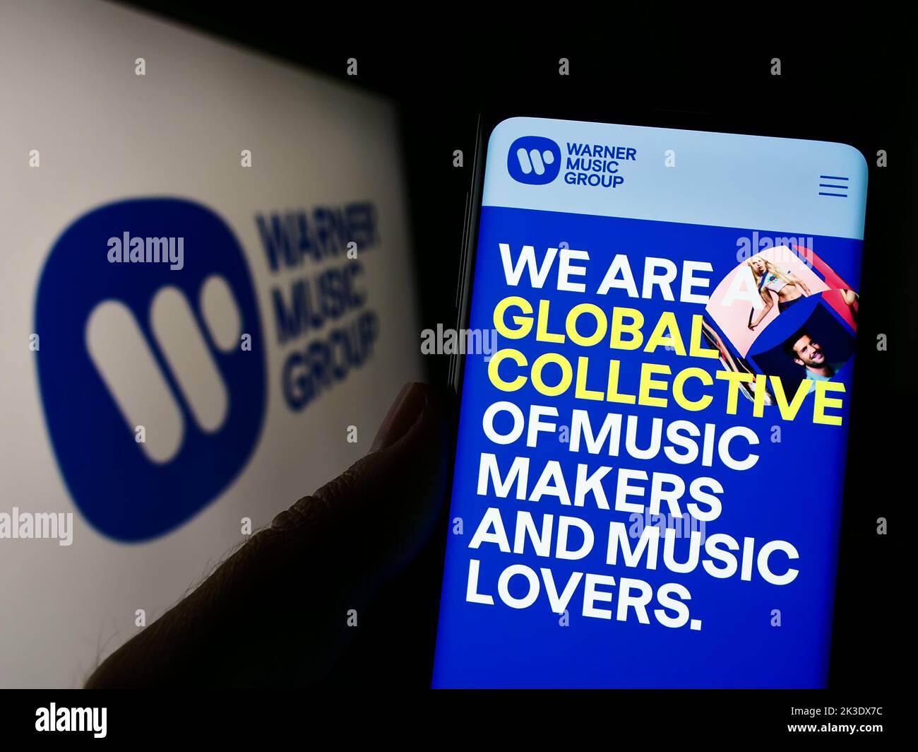 Persona che tiene il cellulare con il sito web della società di intrattenimento Warner Music Group Corp. Sullo schermo con il logo. Messa a fuoco al centro del display del telefono. Foto Stock