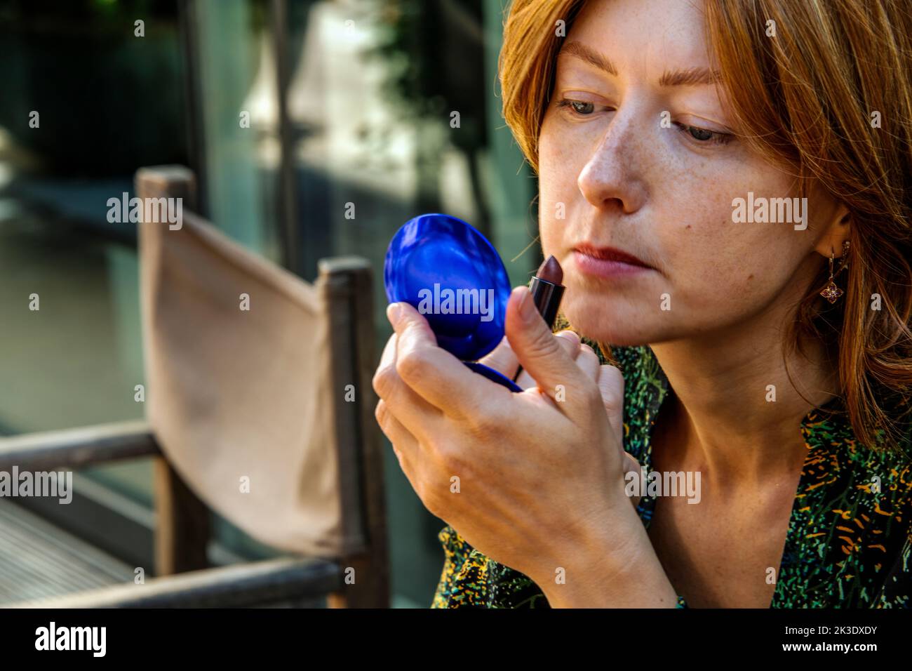 Ritratto di una giovane donna europea che colora le labbra di colore rosso scuro Foto Stock
