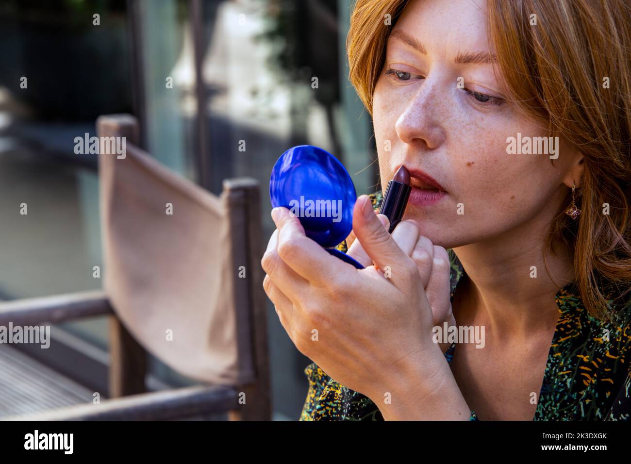 Ritratto di una giovane donna europea che colora le labbra di colore rosso scuro Foto Stock