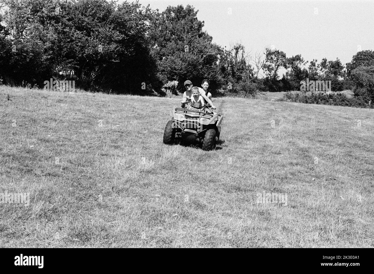 Contadino e due ragazzi in quad, High Bickington, North Devon, Inghilterra, Regno Unito. Foto Stock