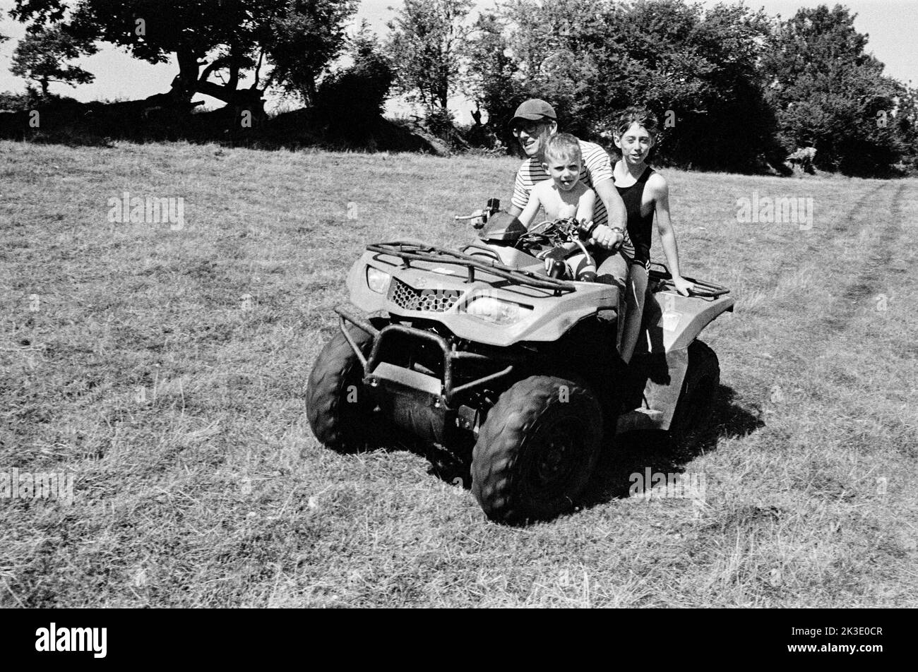 Contadino e due ragazzi in quad, High Bickington, North Devon, Inghilterra, Regno Unito. Foto Stock