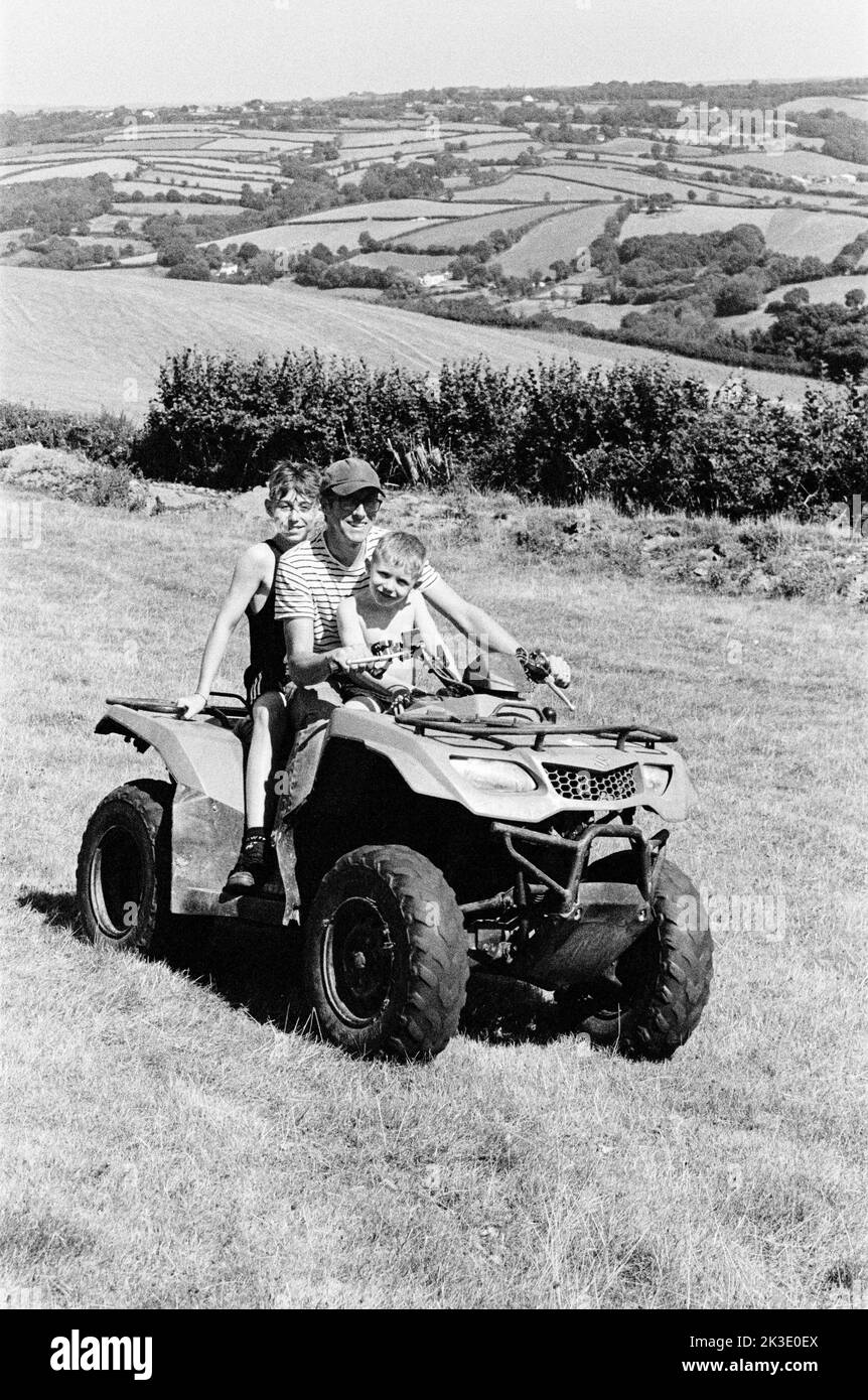 Contadino e due ragazzi in quad, High Bickington, North Devon, Inghilterra, Regno Unito. Foto Stock