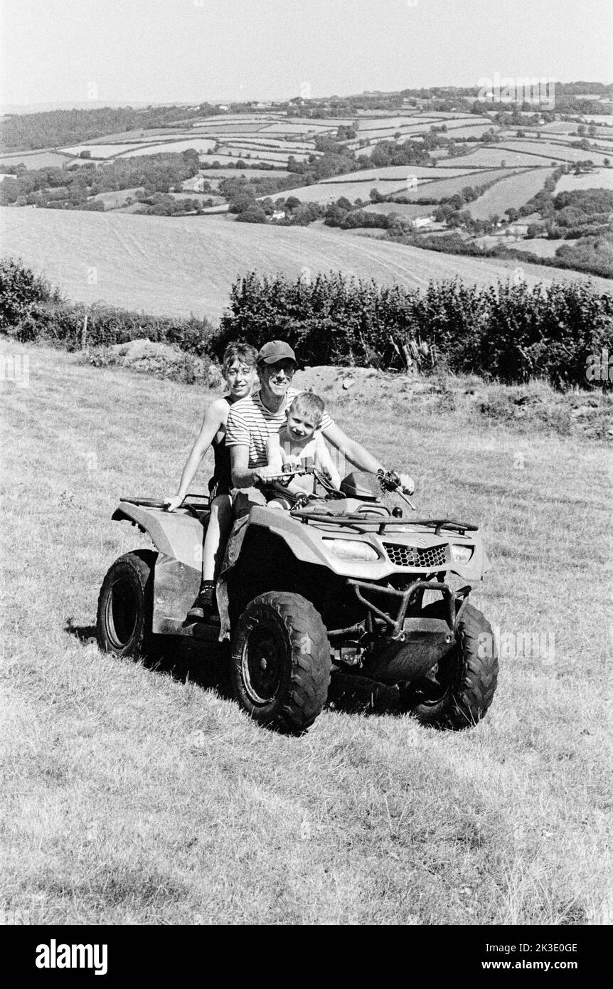 Contadino e due ragazzi in quad, High Bickington, North Devon, Inghilterra, Regno Unito. Foto Stock