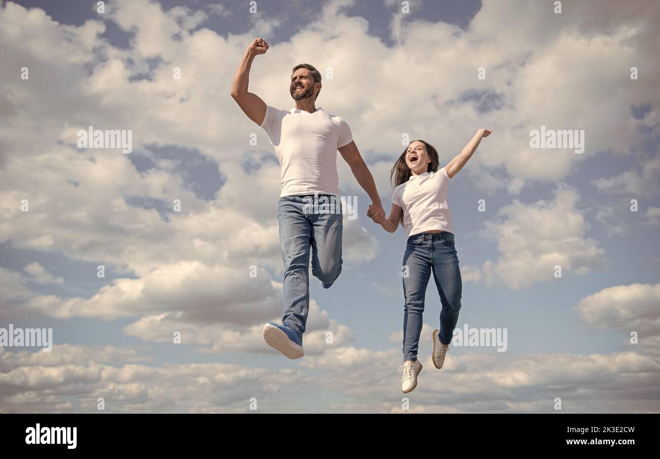 felice padre e figlia saltano nel cielo. luminoso futuro Foto Stock