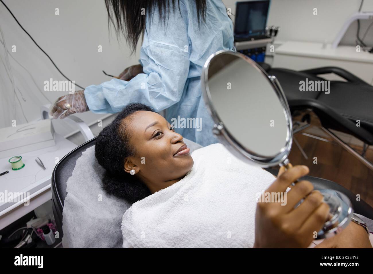Sorridente cliente femminile con specchio che ottiene la cera di fronte in salone di bellezza Foto Stock