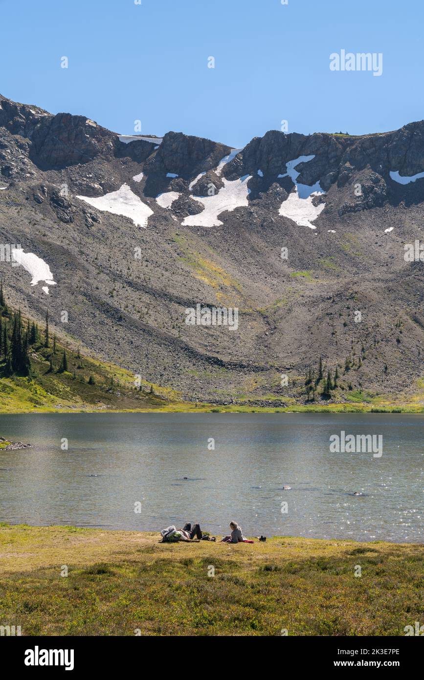 Gli escursionisti si rilassano in un tranquillo lago alpino nel cuore degli aspri paesaggi della Columbia Britannica. Foto Stock