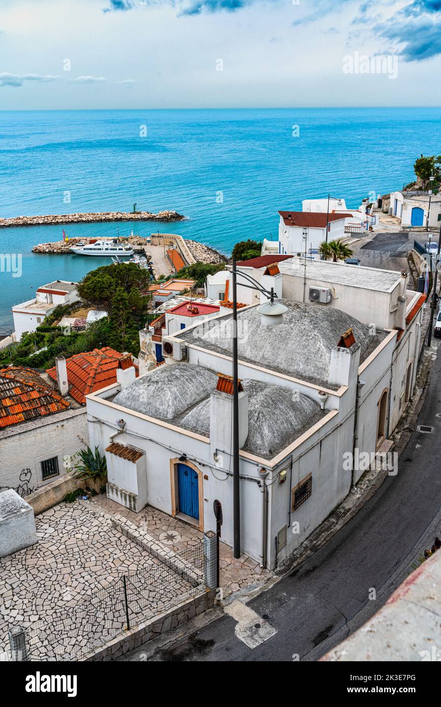 Vista sul borgo peschereccio di Peschici con porte e finestre blu. Sullo sfondo il porto della città. Peschici, provincia di Foggia, Puglia, Italia, Foto Stock