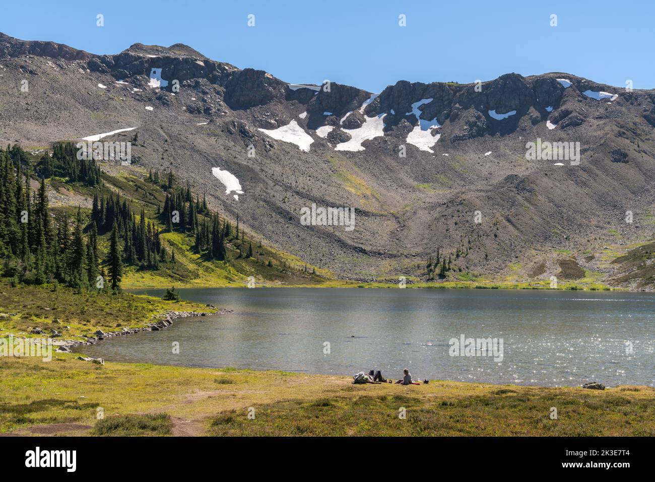 Gli escursionisti apprezzano il tranquillo lago alpino lungo il Panorama Ridge Trail nella Columbia Britannica. Foto Stock