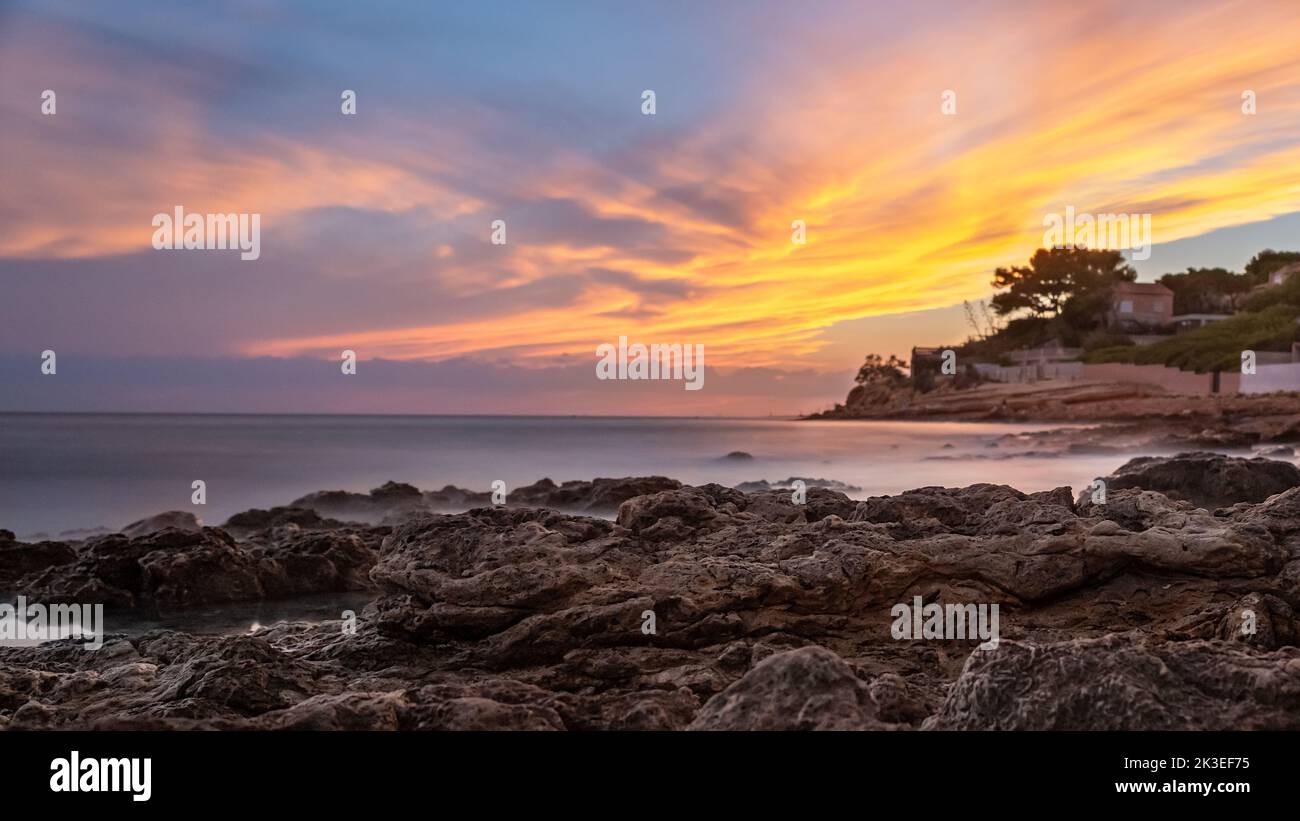 Lunga esposizione di spettacolari tramonti sulla spiaggia con grandi rocce Foto Stock