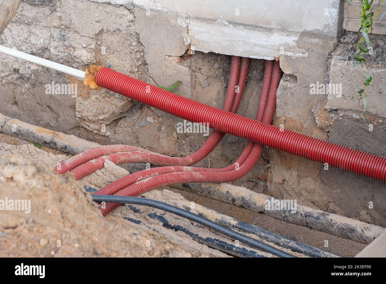 I cavi elettrici nel tubo corrugato rosso sono interrati nella strada.  installazione dell'infrastruttura dei cavi elettrici. Cantiere con molto  Foto stock - Alamy