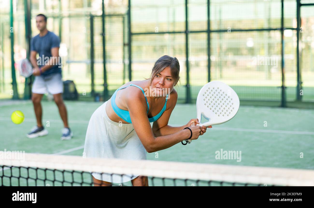 Giovane donna che colpisce il dorso di due mani durante la partita di paddle tennis Foto Stock