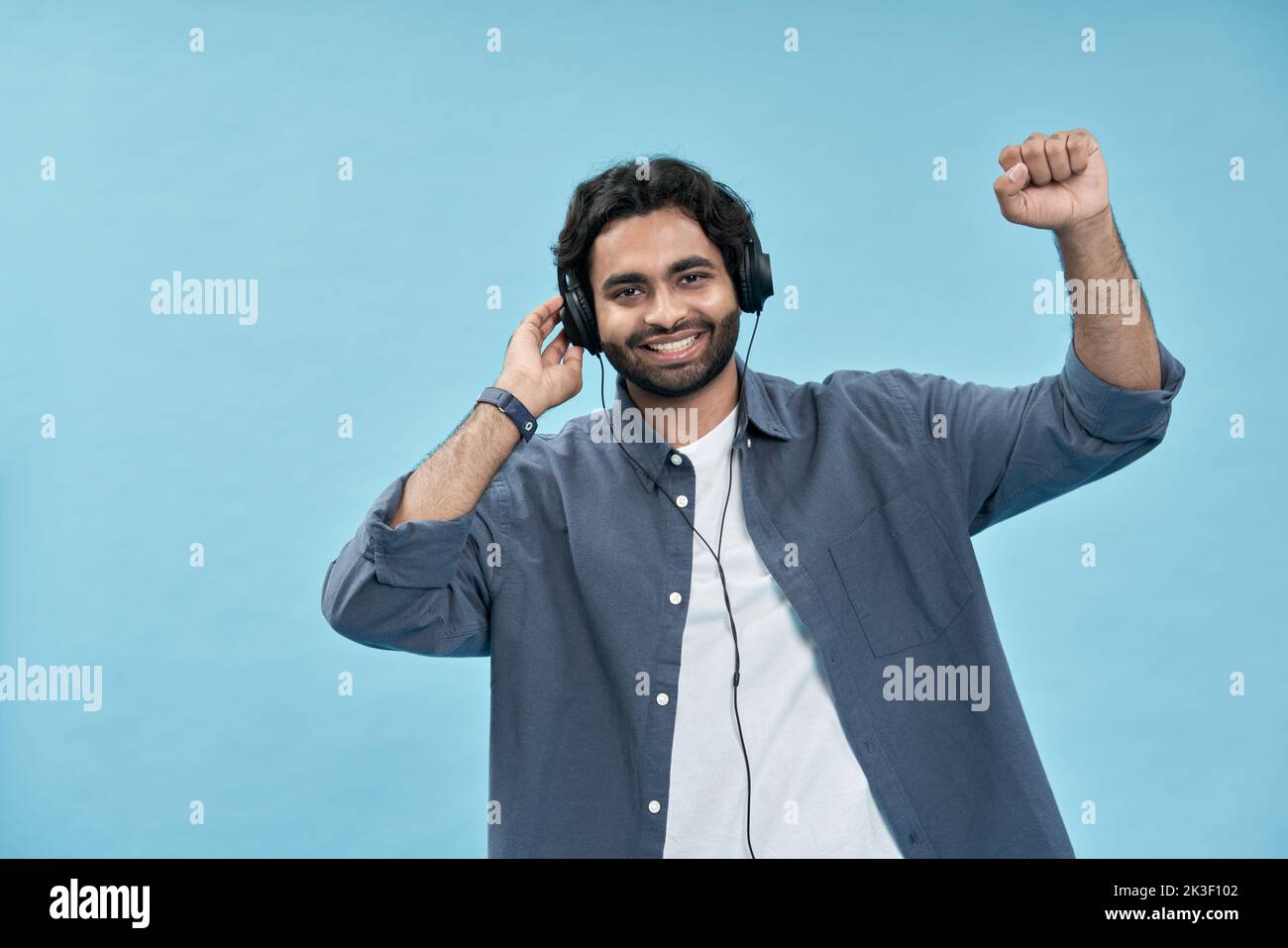 Felice uomo arabo che indossa cuffie ascoltare musica danzare isolato su blu. Foto Stock