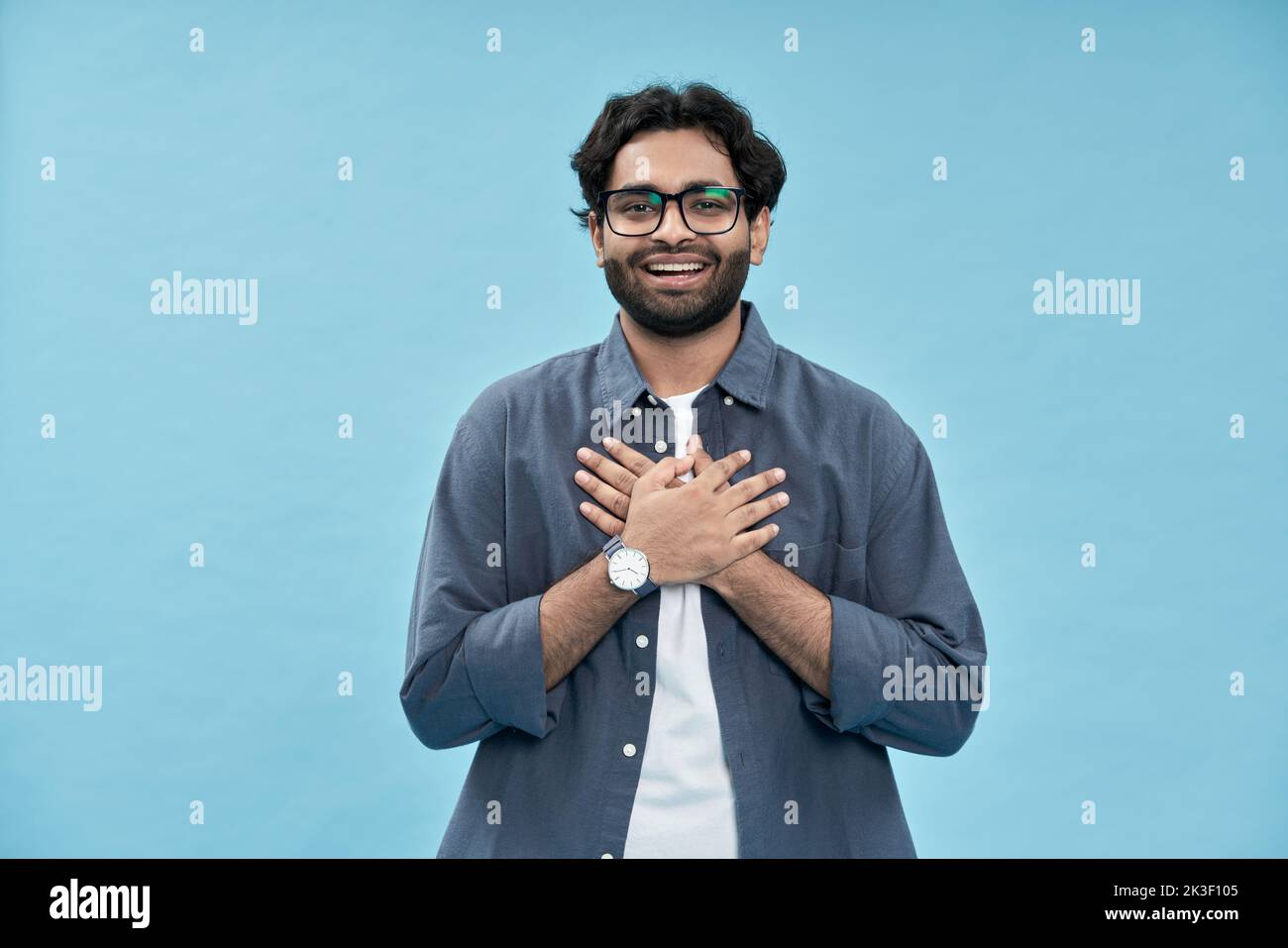 Felice uomo arabo grato tenendo le mani sul petto isolato sul giallo. Foto Stock