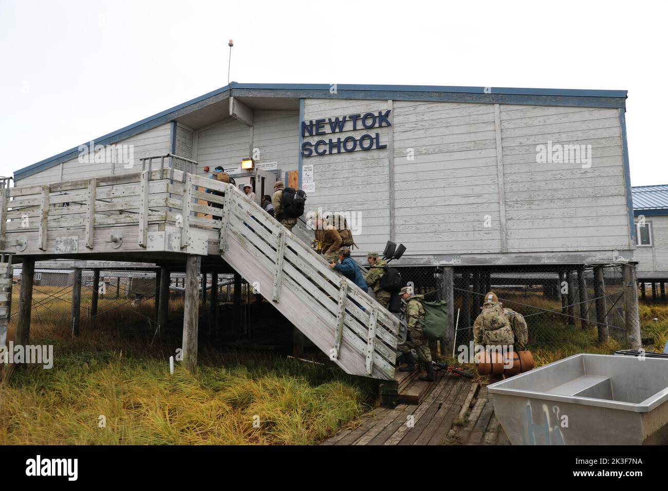 I soldati statunitensi con la Guardia Nazionale dell'Alaska entrano nella scuola locale dopo l'atterraggio per aiutare i residenti locali a ripulire i loro abitanti dopo il Typhoon Merbok, 22 settembre 2022 a Newtok, Alaska. I remoti villaggi nativi dell'Alaska subirono un'inondazione in oltre 1.000 chilometri di costa dell'Alaska. Foto Stock