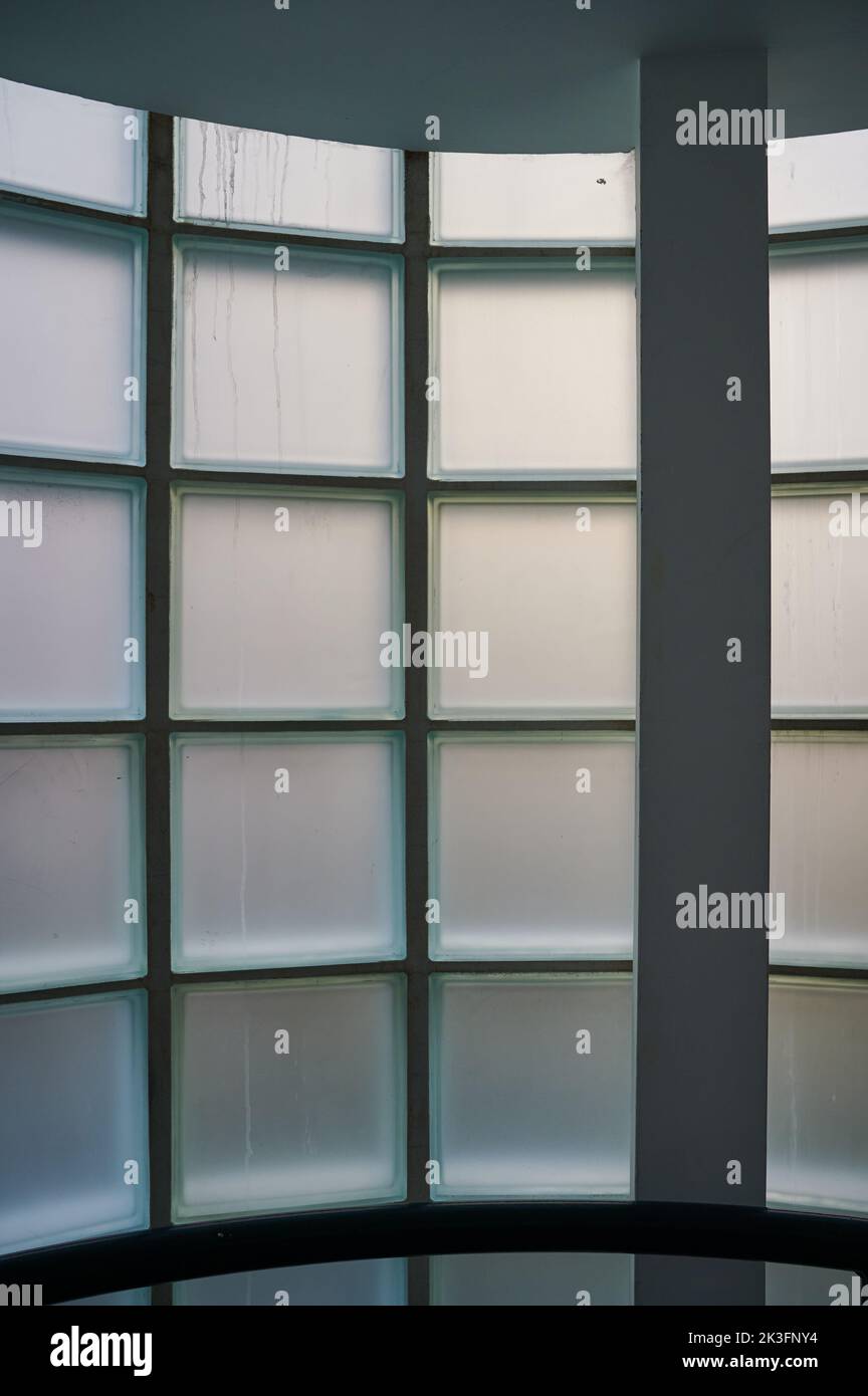Interno dell'edificio che guarda ad una finestra opaca e curva costruita con blocchi di vetro durante il giorno Foto Stock