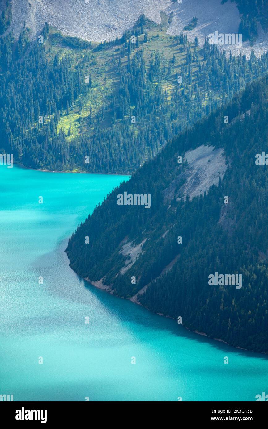 Splendido lago turchese con ripide montagne ricoperte di pini. Foto Stock