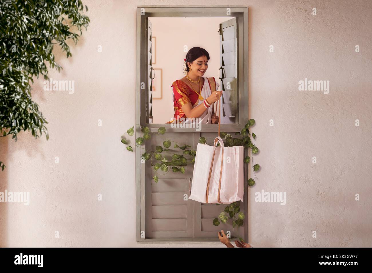 Bengalese donna in piedi alla finestra e tirando la borsa della spesa con una corda Foto Stock