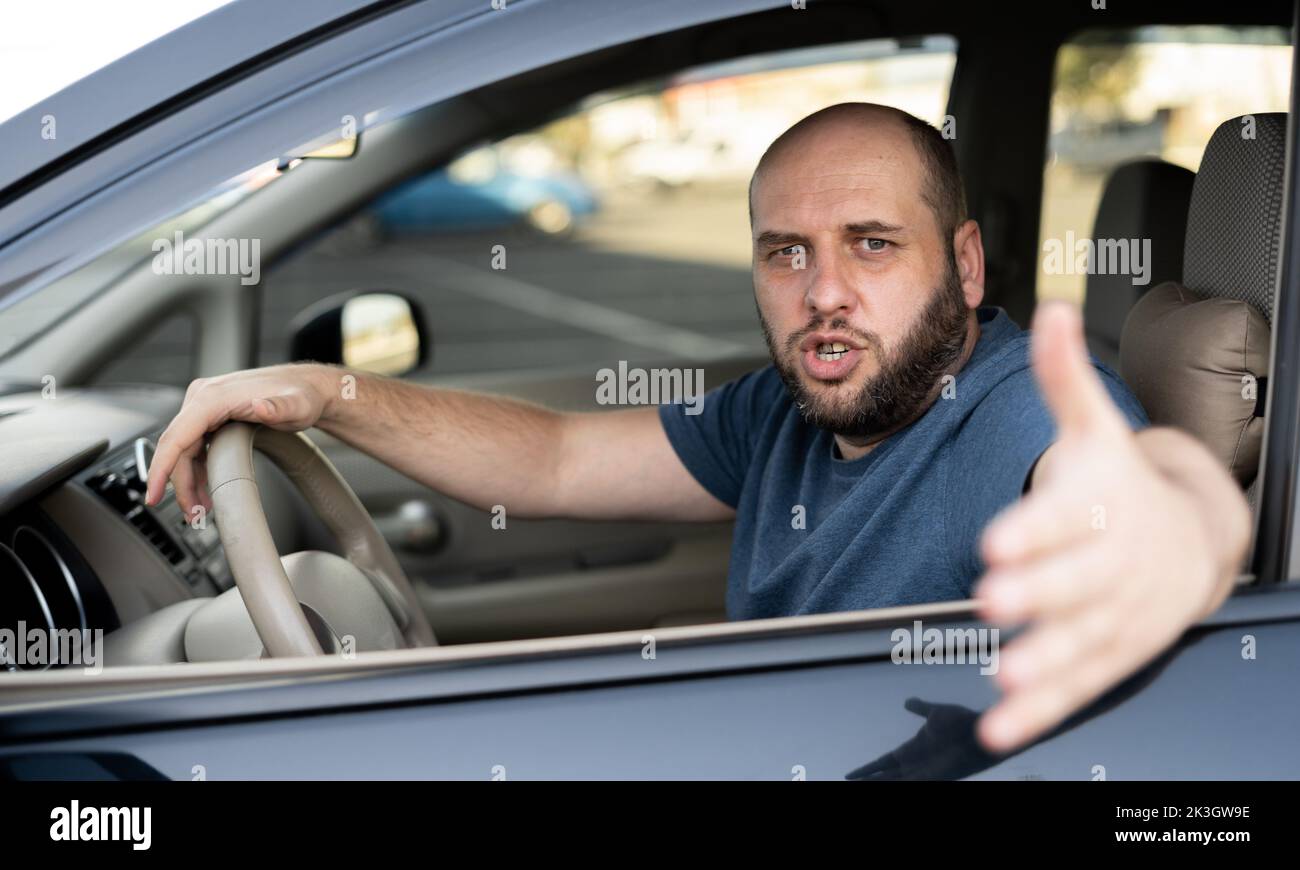 Uomo irritato alla guida di un'auto. Irritato conducente arrabbiato su strada Foto Stock