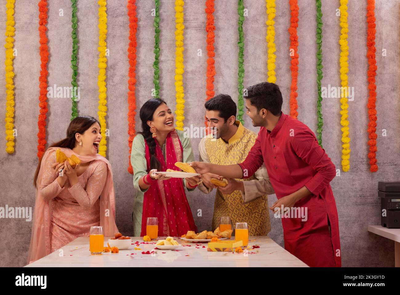 Colleghi che mangiano insieme polpette di aloo in ufficio durante la celebrazione di Diwali Foto Stock